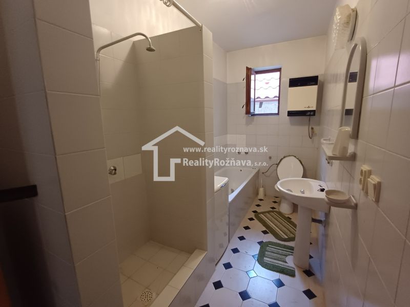 White bathroom with a bathtub, shower, and toilet in a family house.