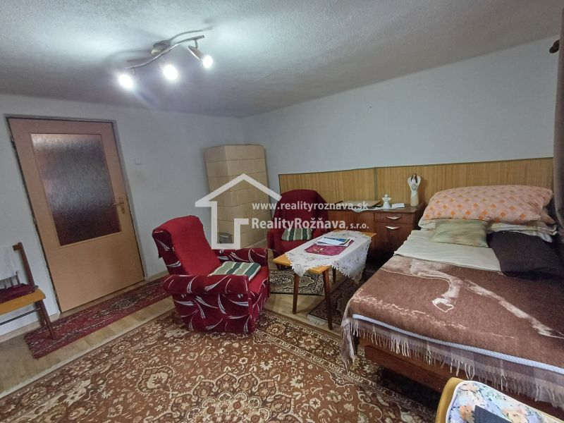 Living room in a family house with an armchair, carpet, and bed.