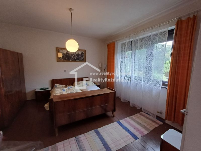 A bedroom in a family house with antique furniture, curtains, and a large window.
