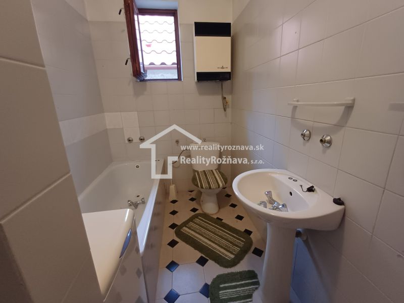 A family house bathroom with a bathtub, sink, and toilet, light tiles.