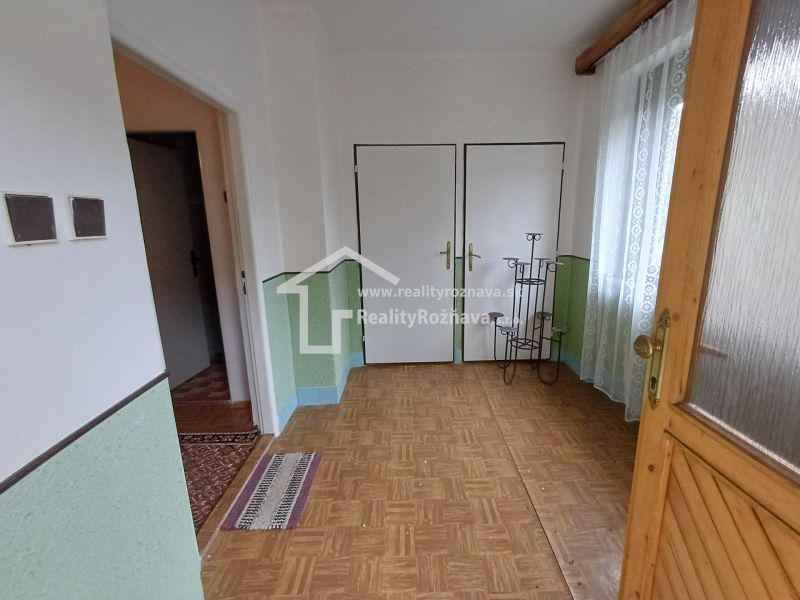 Entrance hallway in a family house with a wooden decor floor, light walls, and curtains.