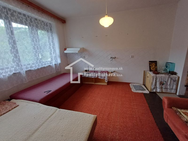 Interior of a family house with a sofa, red carpet, and a large window with a lace curtain.
