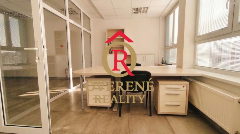 Offices with a large desk, a folding chair, and a simple shelf on the floor with a wooden decor.