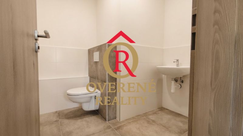 Office restroom with tiled floor and wall-mounted toilet.