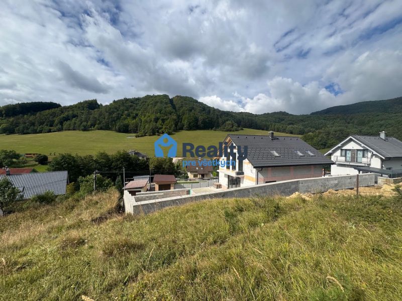 Residential plots in Považská Bystrica with a view of green hills and houses.