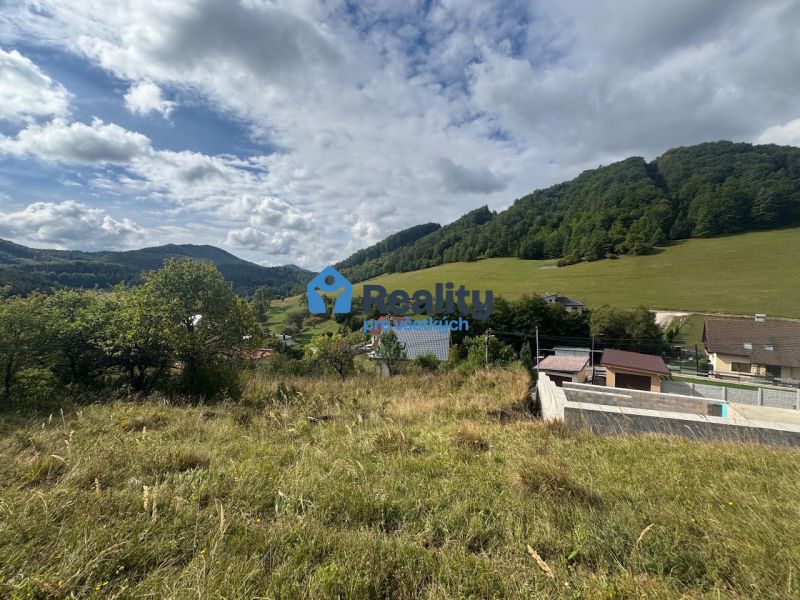 Residential plots in Považská Bystrica with hills and houses in the background.