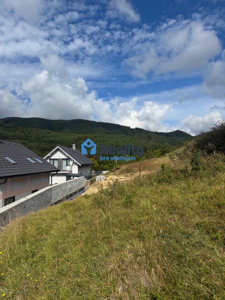 Plots - housing in Považská Bystrica with a view of the mountains and cloudy sky.