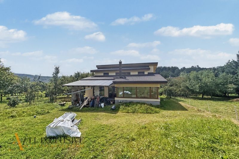 A family house in Veličná with an extensive lawn and surrounding trees.