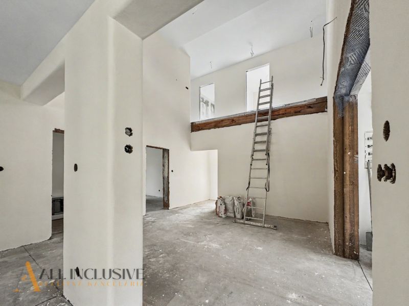 The interior of a family house under construction with a ladder and white walls.