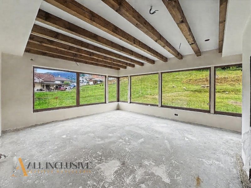 Interior of a family house with large windows and wooden beams on the ceiling.