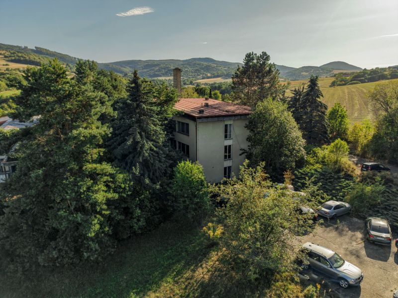 A building surrounded by trees and cars in the picturesque landscape of Slatinské Lazovček with development plots.