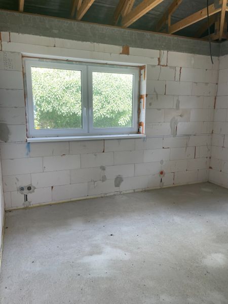 Interior of a family house with a large window, concrete floor, brick walls.