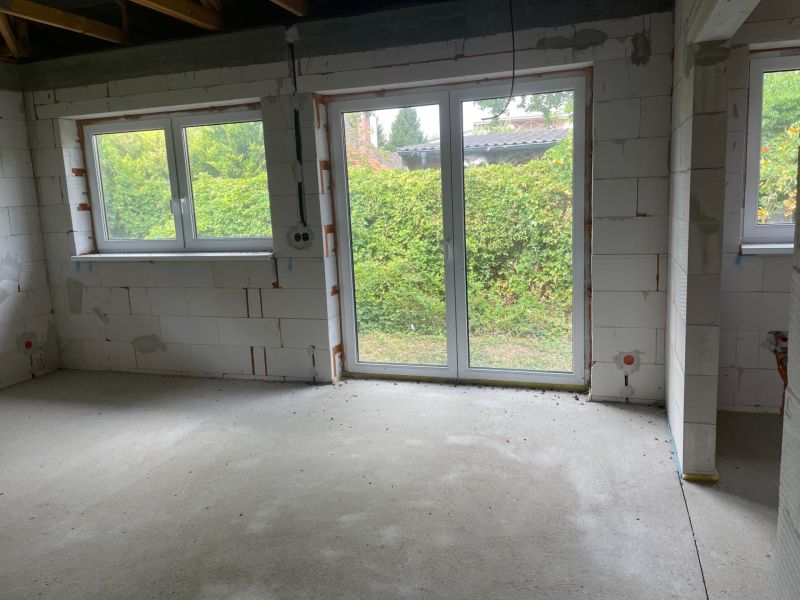 A room in a family house with large windows, view of the green outside.