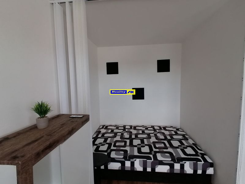 Bed and decoration in a one-room apartment with a wooden decor floor.