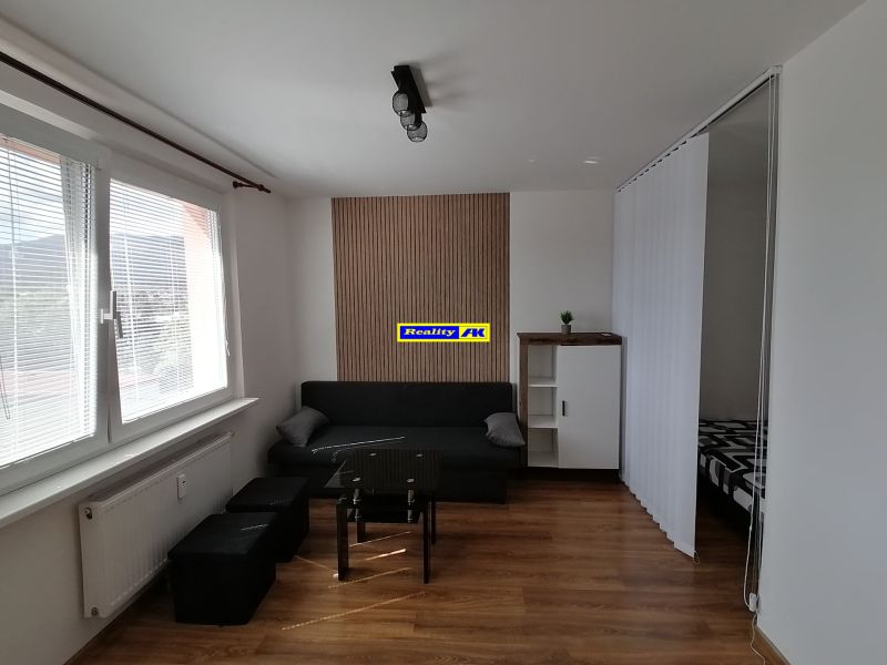 Living room with a sofa, table, and wooden decor flooring in a studio apartment.