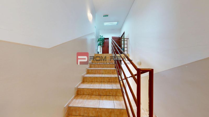 Staircase in Offices with brown tiles and railing.