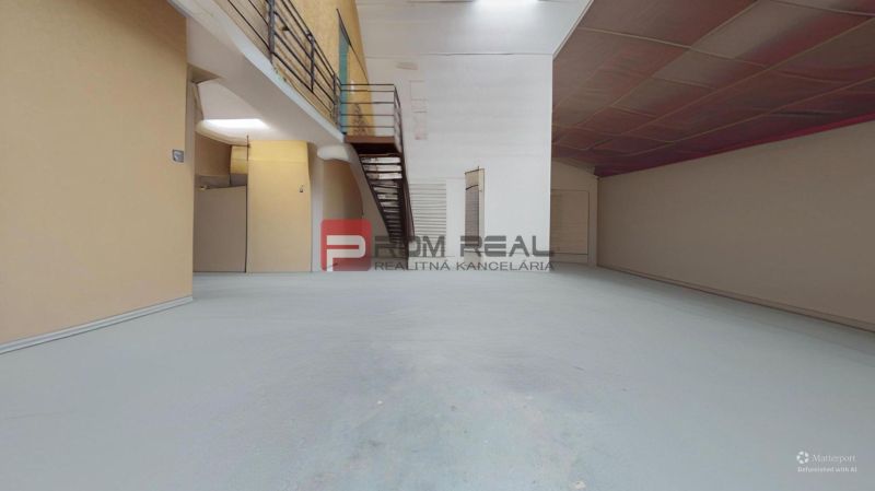 A large warehouse interior with a metal floor, staircase, and storage space.