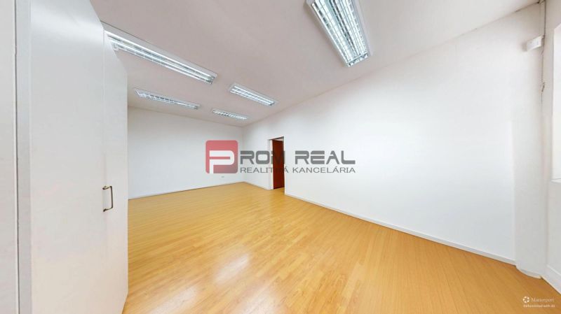 White office with wood-patterned flooring and ceiling lights.