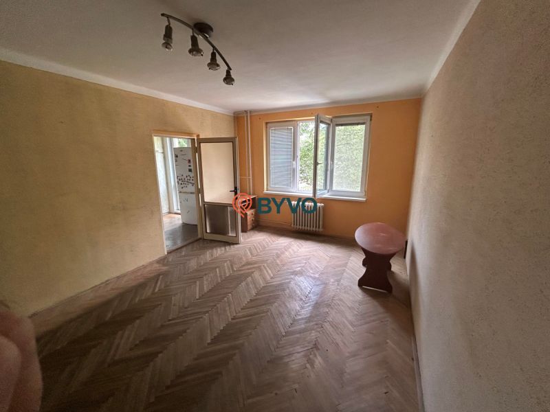 A room in a 3-room apartment with a wooden decor floor and an open window.