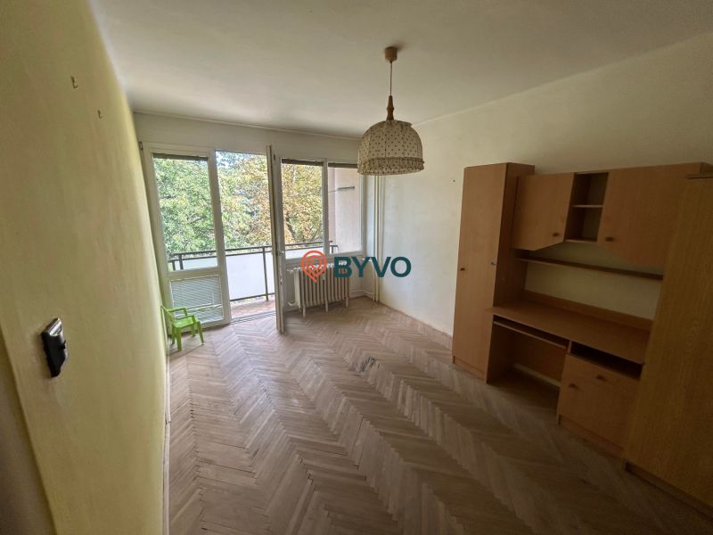 A room with furniture, a wooden decor floor, a balcony in a 3-room apartment.