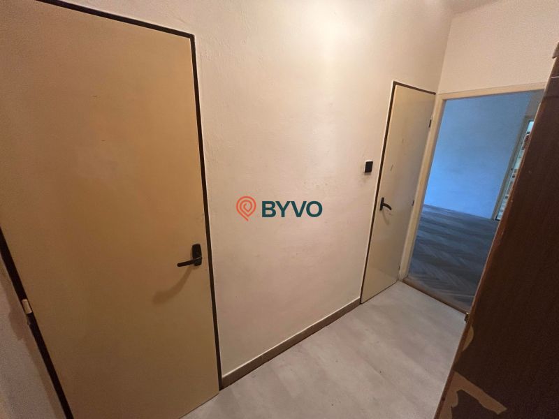 A hallway in a 3-room apartment with a wooden decor floor and two doors.