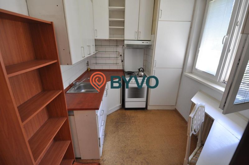 A kitchen in a three-room apartment, with a stove, cabinets, and a floor with a wood decor.