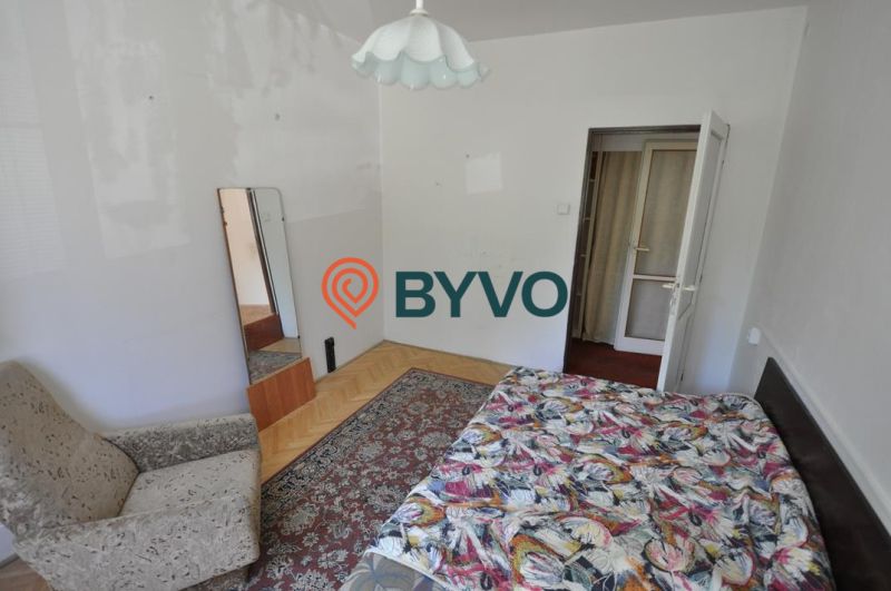 Bedroom in a 3-room apartment with a bed, chair, mirror, and floor with a wooden decor.