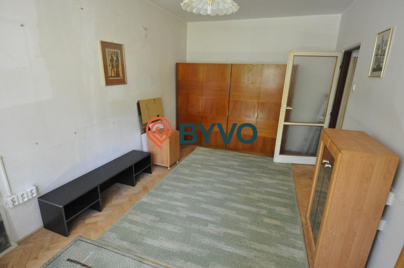 A room in a 3-room apartment with a floor featuring a wood decor and furniture.