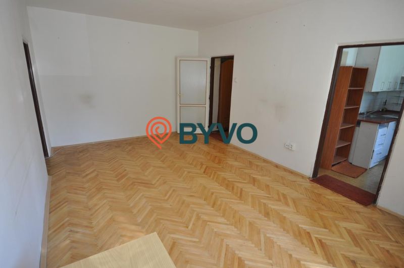 A room with a wooden floor decor and a kitchen, 3-room apartment.