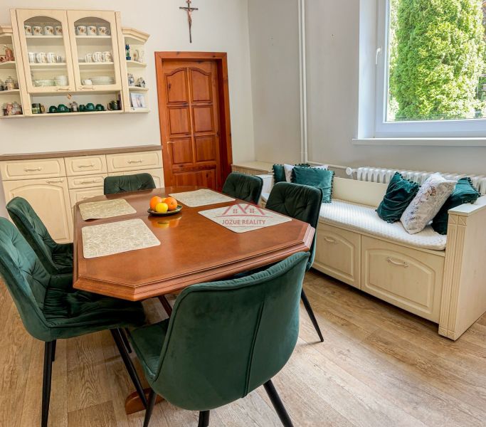 A family house with a dining table, green chairs, and a wooden decor floor.