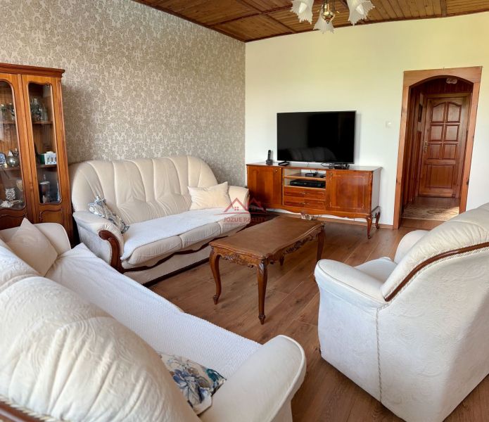 Living room in a family house with wood-patterned flooring and cream furniture.