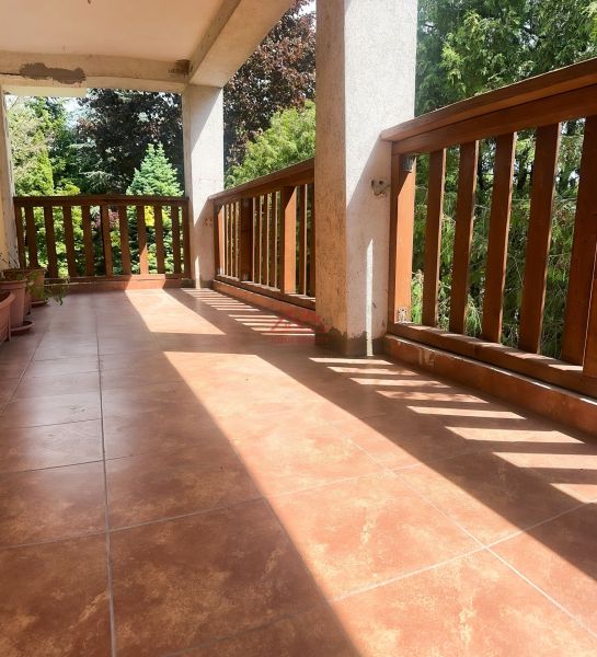 A balcony of a family house in Sady nad Torysou with brick paving and wooden railing.