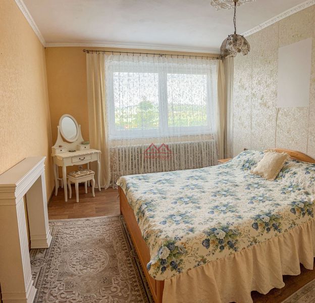Bedroom in a family house with a wooden decor floor, floral bedspread, and a vanity table.