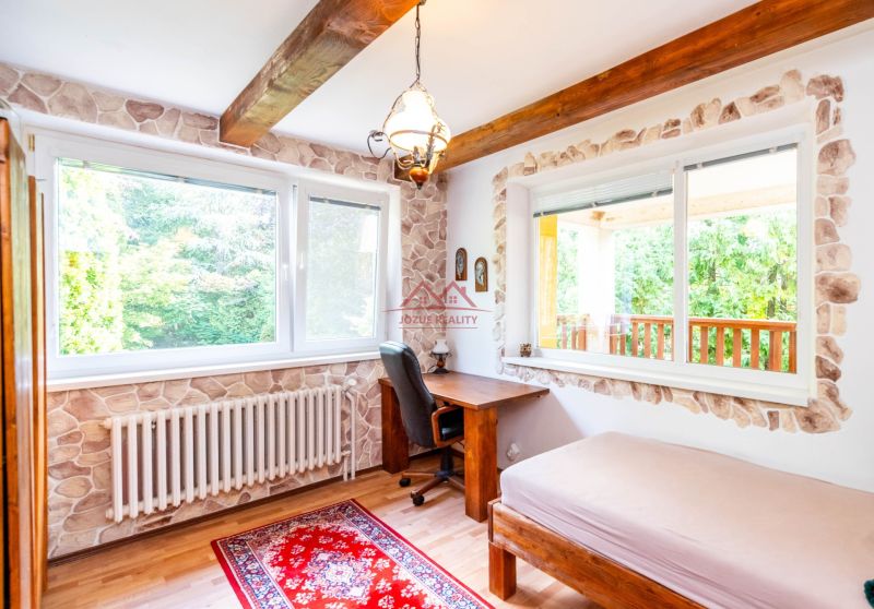A room with a desk, wooden floor decor, and large windows in a family house.