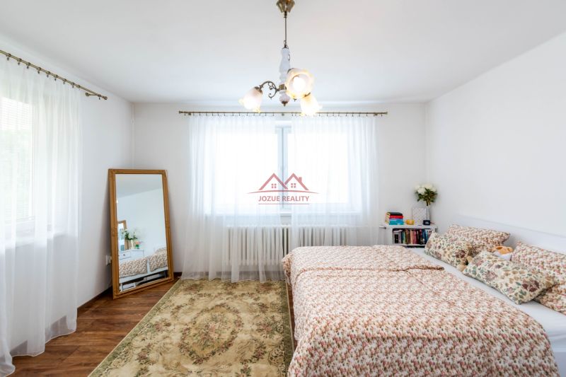 A bright bedroom with a large mirror and a patterned carpet in a family house.