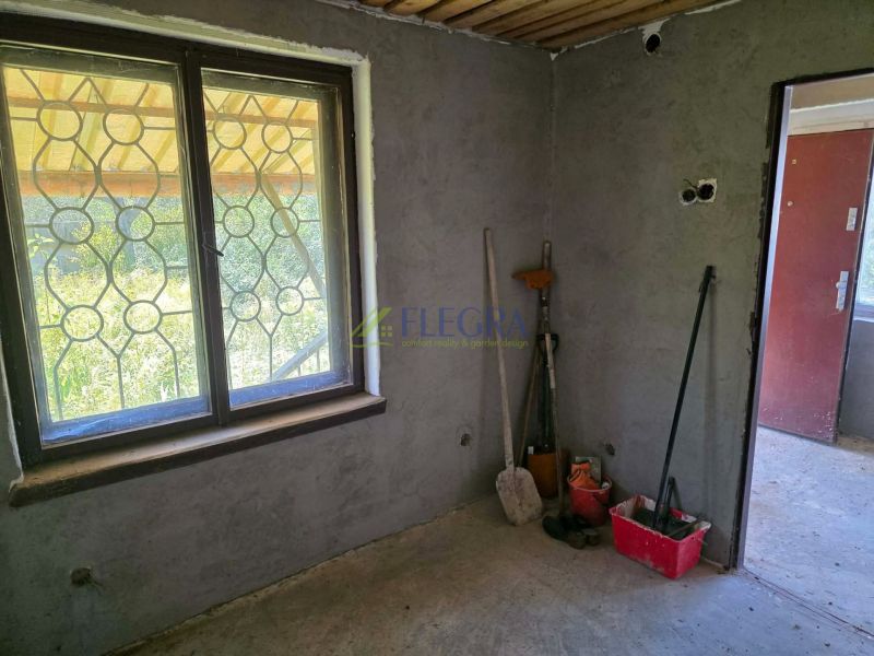 The interior of a cabin with a window, tools, and a bucket on the floor with wooden decor.