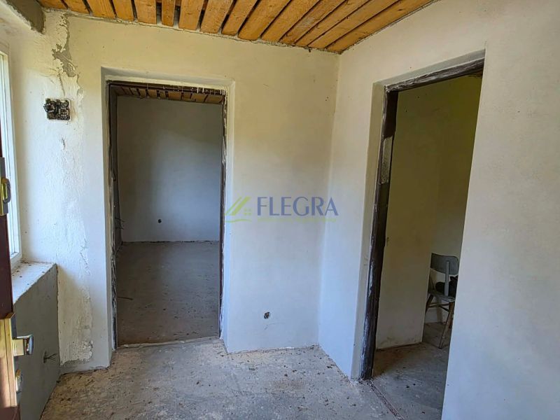 The interior of a cabin with bare walls, a concrete floor, and a wooden ceiling.