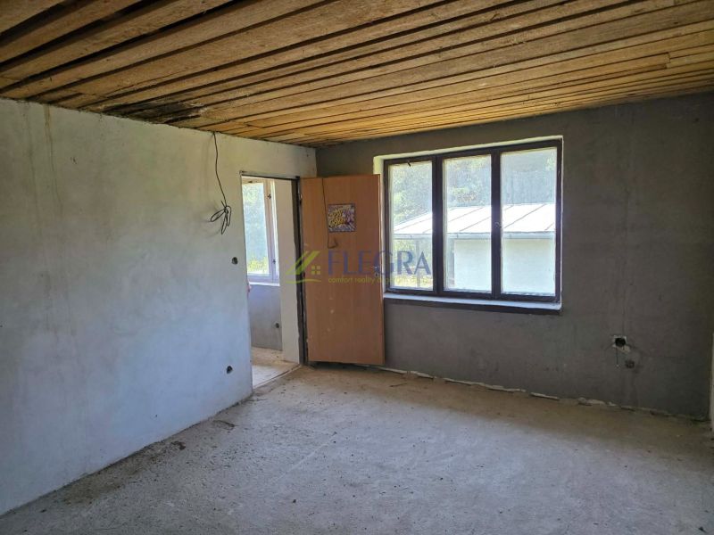 The interior of the cabin with a concrete floor, empty walls, horizontal wooden ceiling.