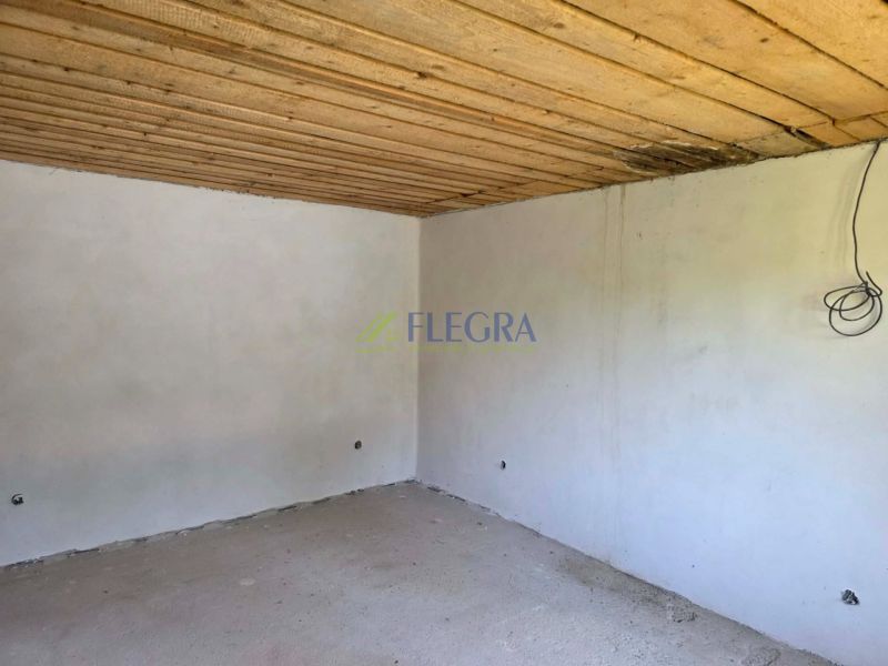 The interior of the cabin with a wooden ceiling and an unfinished floor.