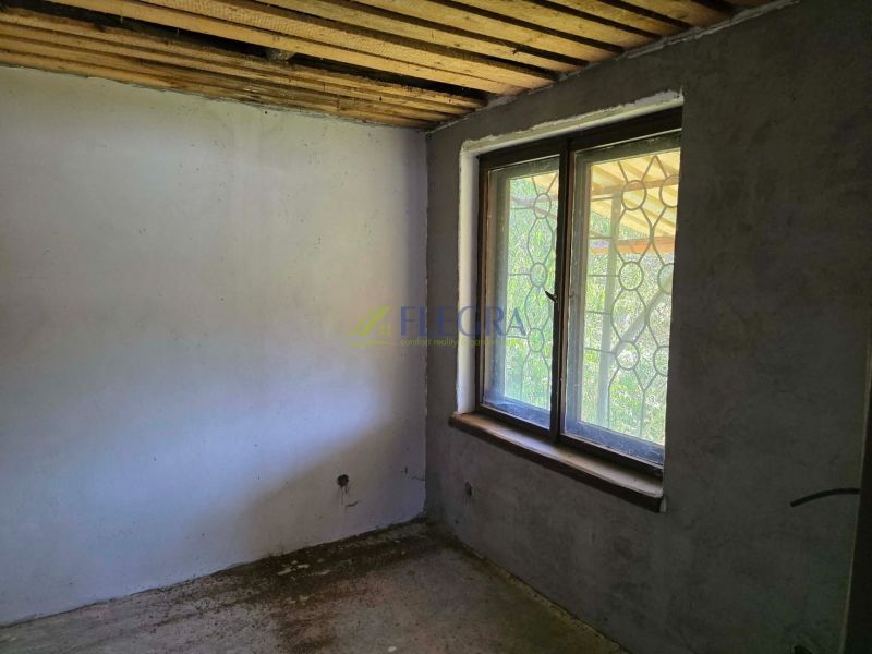 The room in the cottage has a concrete floor and a simple window with a grille.