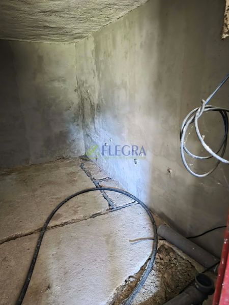 Gray walls in a cabin with a concrete floor and cables on the floor.