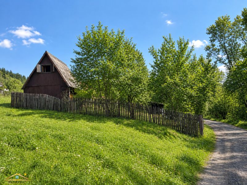 Wooden cottage with a fence on a plot of land near the forest in Radôstka.