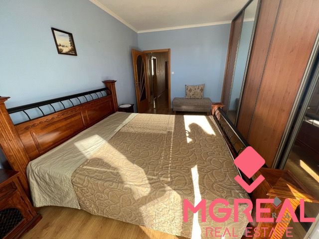 Bedroom in a 3-room apartment with a wooden decor floor and a large bed.