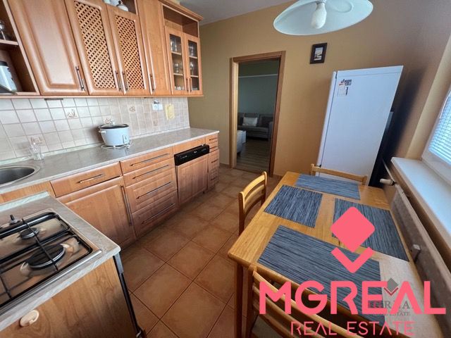 A kitchen in a 3-room apartment with wooden cabinets and ceramic flooring.
