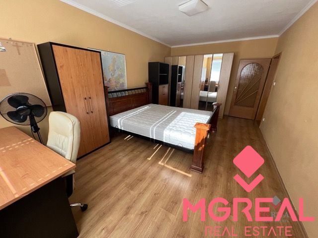 Bedroom with wood-patterned flooring in a 3-room apartment, with a bed and a desk.