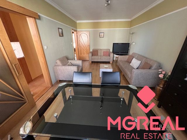 Living room in a three-room apartment with sofas and a glass table, floor with wood decor.