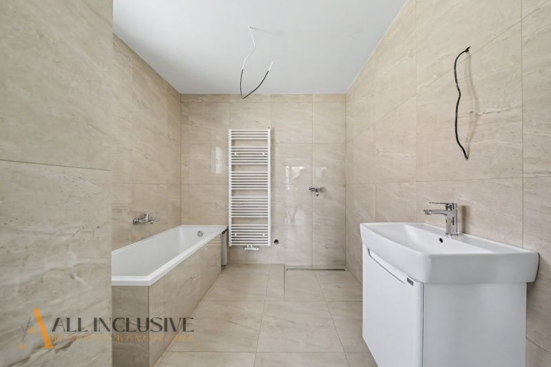 A bathroom in a family house with a bathtub, sink, and radiator on light tiles.