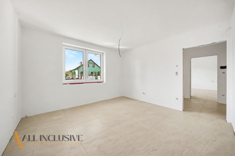 A bright room with a large window and wood-patterned flooring in a family house.