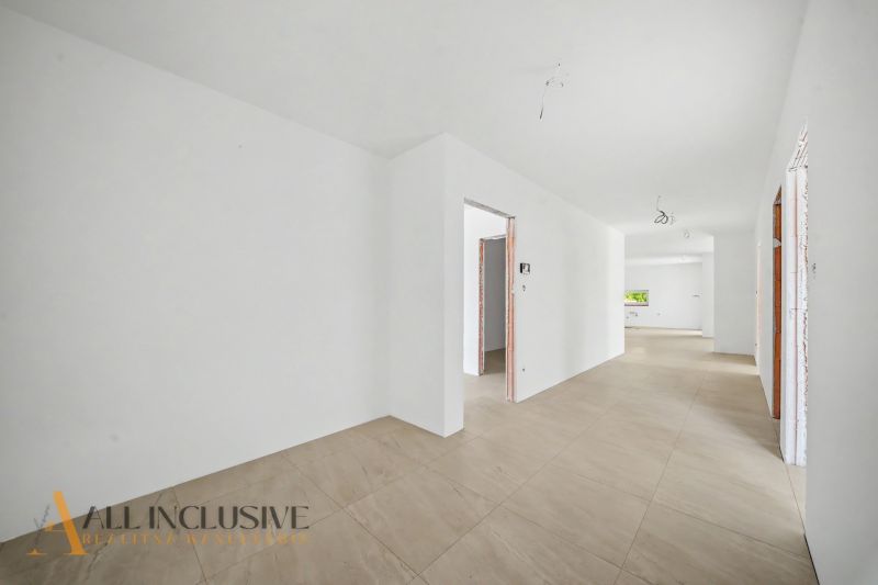 A hallway in a family house with a wooden decor floor and white walls.