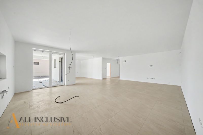 A spacious room with a wood-patterned floor, large window, and white walls.